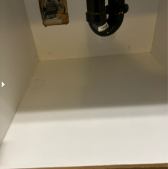 Under-sink cabinet after deep cleaning in Abbotsford. Spotless white interior